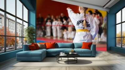 An athlete in a kimono with a yellow belt demonstrates martial arts techniques. Inscription on the jacket - Taekwondo Wall mural