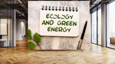 Between two sheets from a notebook on a green strip with the inscription - Ecology And Green Energy Wall mural