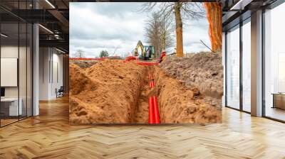 Network cables in red corrugated pipe are buried underground on the street. underground electric cable infrastructure installation. Wall mural