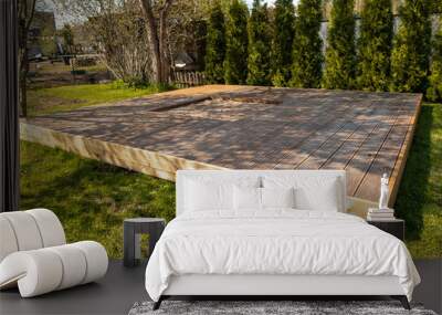 Wooden deck with central sandpit in a backyard setting, surrounded by trees and natural surroundings Wall mural