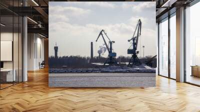 Logistics and transportation  Cargo ship with ports crane bridge coming in port and transportation industry winter suny day in Latvia baltic sea an river daugava. Wall mural