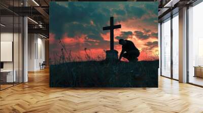 Concept of a man kneeling and praying in front of a cross. Wall mural