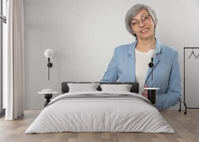 Elderly woman posing in a studio against a light background with copy space Wall mural