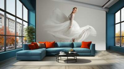 Beautiful attractive bride in wedding dress with long full skirt, white background, dance and smile Wall mural