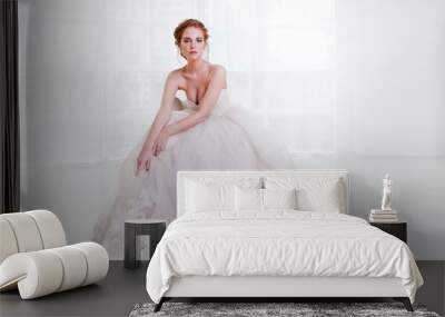 Portrait of a beautiful girl in a wedding dress. Bride in luxurious dress sitting on a chair Wall mural