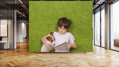 Child embracing friendly dog jack russell was reading the book Wall mural