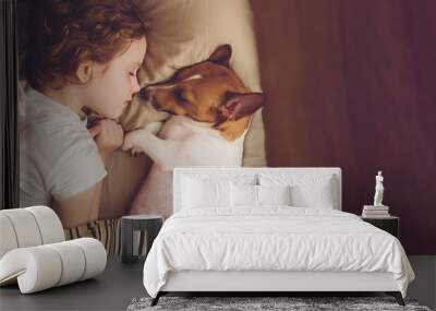 Sweet curly girl and jack russell dog is sleeping in night. Wall mural