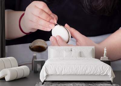 Female hands paints a white Easter egg according to german tradition with a trimmed goose quill and melted bees wax along a rubber ring Wall mural