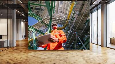 a man worker engineer conducts a site inspection at an industrial facility of gas and oil petroleum industry with utilizing a tablet for data management. technology and safety in maintaining operation Wall mural