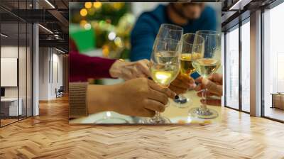 close up glasses of clinking glasses of champagne with lighting. Dinner party with drinking of champagne. hands holding clear glass with alcohol in yellow shine reflect. Wall mural