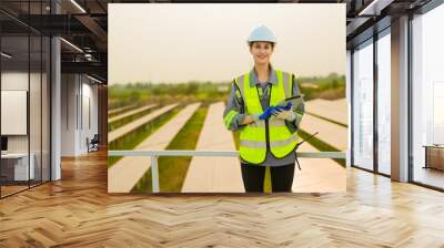 engineer woman standing at solar farm or photovoltaic cell construction. Industrial Renewable energy of green power. factory worker working on solar farm. Wall mural