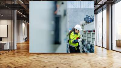 female engineers in neat work clothes prepare and control the production system of large modern machines in a factory producing industrial technology products. Wall mural