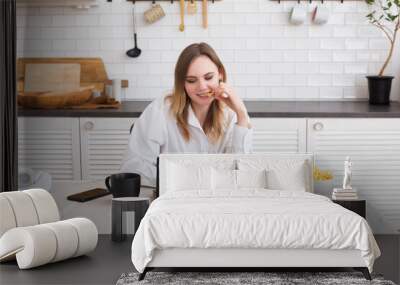 attractive young woman working with laptop and eating fast food in the kitchen. Unhealthy Lifestyle woman has pizza for lunch. home office. Wall mural