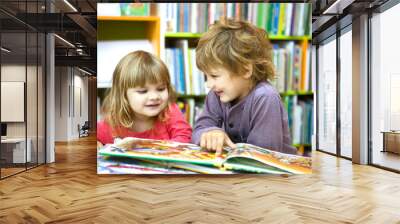 Cute two little kids, brother and sister  reading a book together in library Wall mural