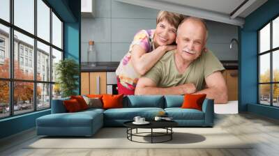 Happy and smiling senior couple in love embracing in kitchen. Wall mural