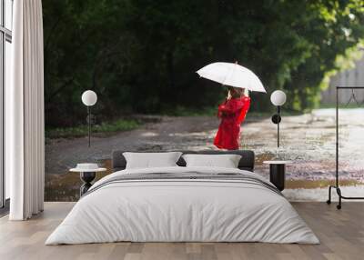 Happy child  with an umbrella playing out in the rain in the summer outdoors Wall mural