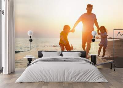 happy  family father and two children playing on the beach  run at the sunset time.  Wall mural