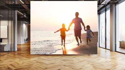 happy  family father and two children playing on the beach  run at the sunset time.  Wall mural