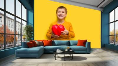 Happy kid boy hold  a heart on yellow background.  St. Valentine's comcept. banner. Copy space. Mom's Day Wall mural