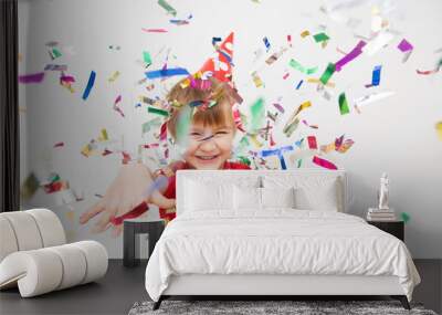 Little boy having fun celebrating birthday. Portrait of a child throws up multi-colored tinsel and confetti. Positive emotions. Wall mural