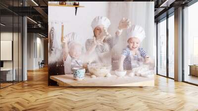 mother and two little childrens are cooking cookies and having fun in the kitchen. Wall mural