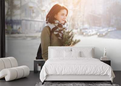 Outdoor portrait of beautiful happy smiling young woman with Christmas gifts on street. Wall mural