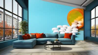 An orange prescription bottle tipped over with white pills spilling out onto a blue surface, suggesting a medical or pharmaceutical theme. Wall mural