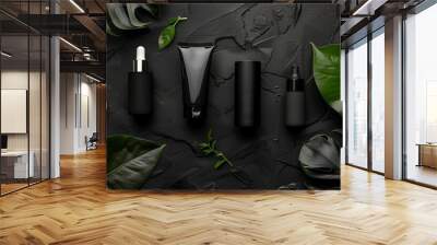 Elegantly styled skincare products in sleek black packaging with lush green leaves on a textured dark background. Wall mural