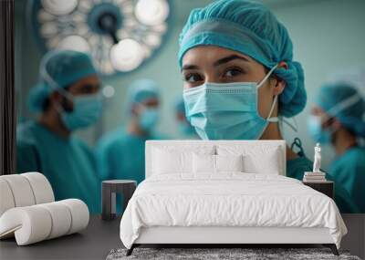 Female medical professional in surgical gear smiles at the camera; colleagues, also in scrubs, are focused on their tasks in the background. Wall mural