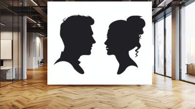 Silhouettes of a man and woman facing each other against a plain white background. Wall mural