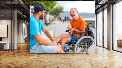 A disabled person in a wheelchair with a friend on summer vacation having fun laughing a lot by the sea Wall mural