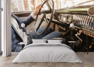 A man in a suit is driving a car with a black steering wheel Wall mural