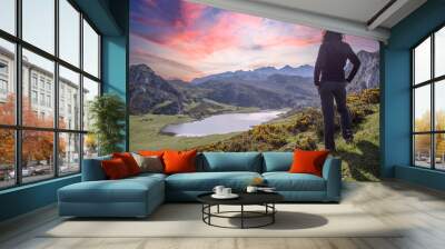 A young woman looking at the beautiful Covadonga lake in Asturias in a beautiful spring sunset, Picos de Europa. Spain Wall mural