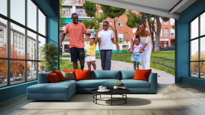 African black ethnicity family with children on playground, having fun in city park Wall mural