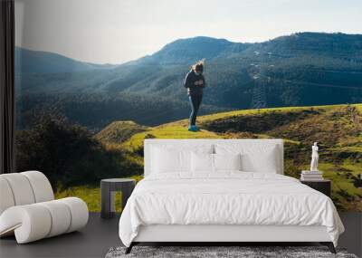 Shot of a girl in a protective medical mask standing in mountains  -  pandemic tourism Wall mural