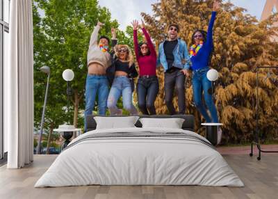 Group of multi ethnic friends having a party in a park - Diverse young people jumping for joy in a summer party portrait - Happy hour, lunch break and youth concept Wall mural