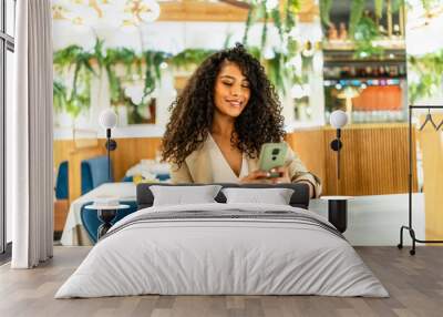 Smiling woman using date app sitting on a cafeteria Wall mural