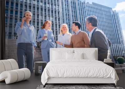 Speaking in a relaxed moment at halftime. Group of coworkers outdoors in a corporate office area Wall mural