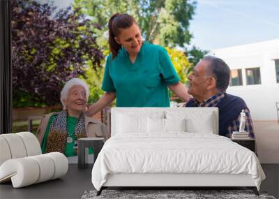 Two elderly people with the nurse in the garden of a nursing home or retirement home, old man and old woman Wall mural