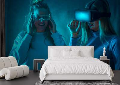 Two futuristic women in vr glasses, enjoying virtual reality, blue background Wall mural