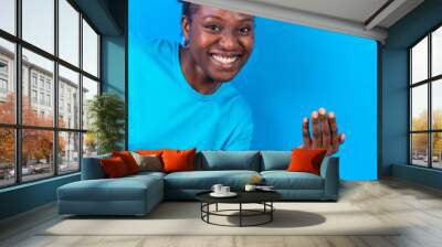 Young african american woman isolated on a blue background inviting to come with her hand Wall mural