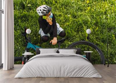 young cyclist with mask, crouched down using smart phone Wall mural