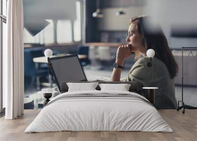 Business woman in a suit working with a laptop at her desk in her home office Wall mural