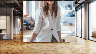 Portrait of smiling woman in white jacket standing leaning on chair. Wall mural