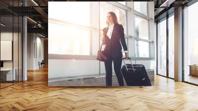 Pretty smiling female flight attendant carrying baggage going to airplane in the airport Wall mural