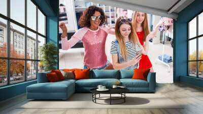 Smiling female friends having fun, making video or selfie while doing a funny dance in fashion showroom Wall mural