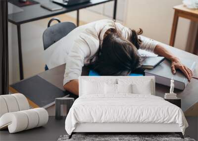 Tired female student sleeping on desk face and hands on books Wall mural