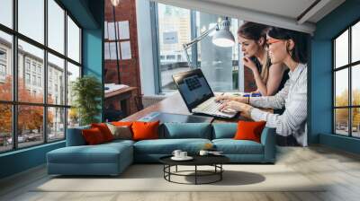 Two women working on new website design choosing pictures using the laptop surfing the internet Wall mural