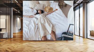 Woman tired but satisfied fell on the bed on a trip Wall mural