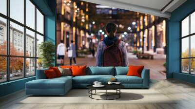 Woman walks through the night city. The view from the back. Wall mural